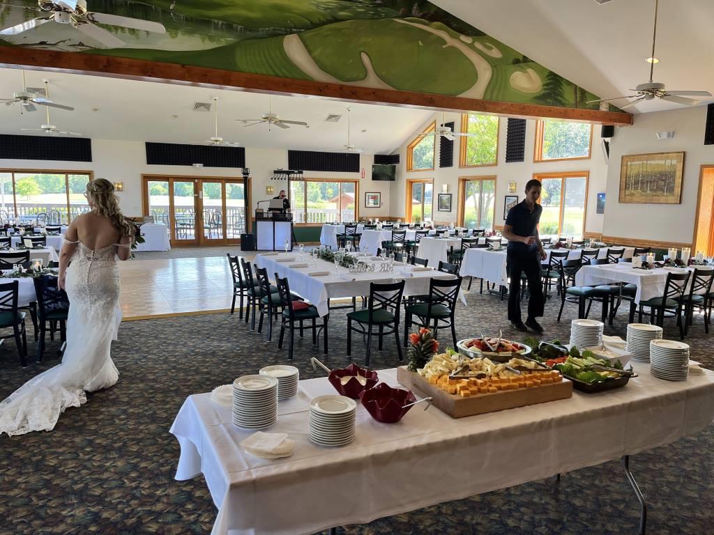 A bride in a wedding dress walks past a buffet table
