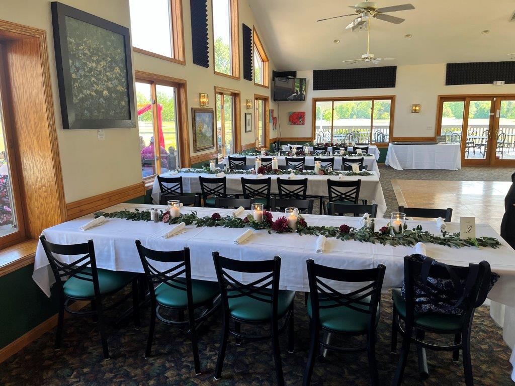 A large room with tables and chairs set up for a wedding reception
