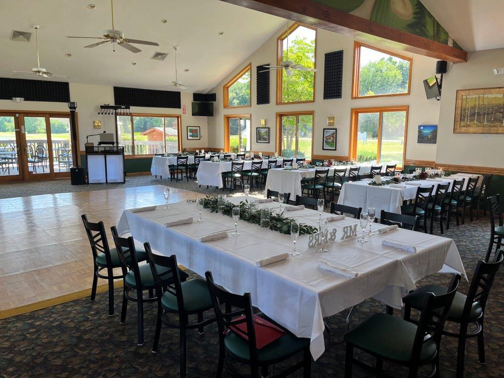 A large room with tables and chairs set up for a wedding reception