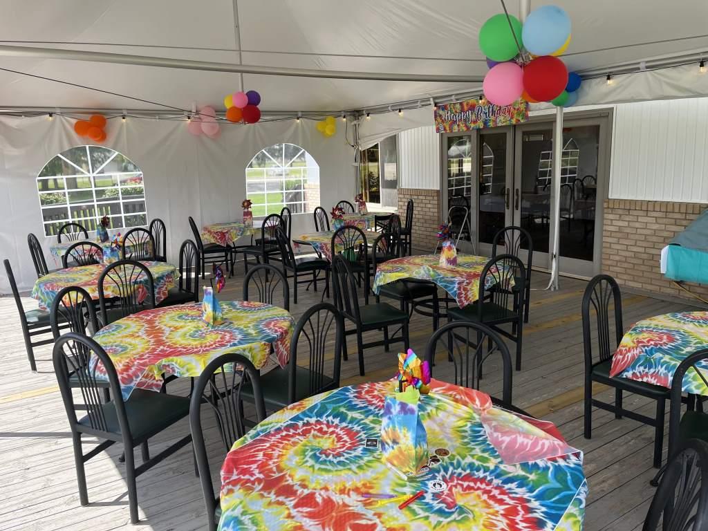Tables and chairs under a tent with balloons hanging from the ceiling