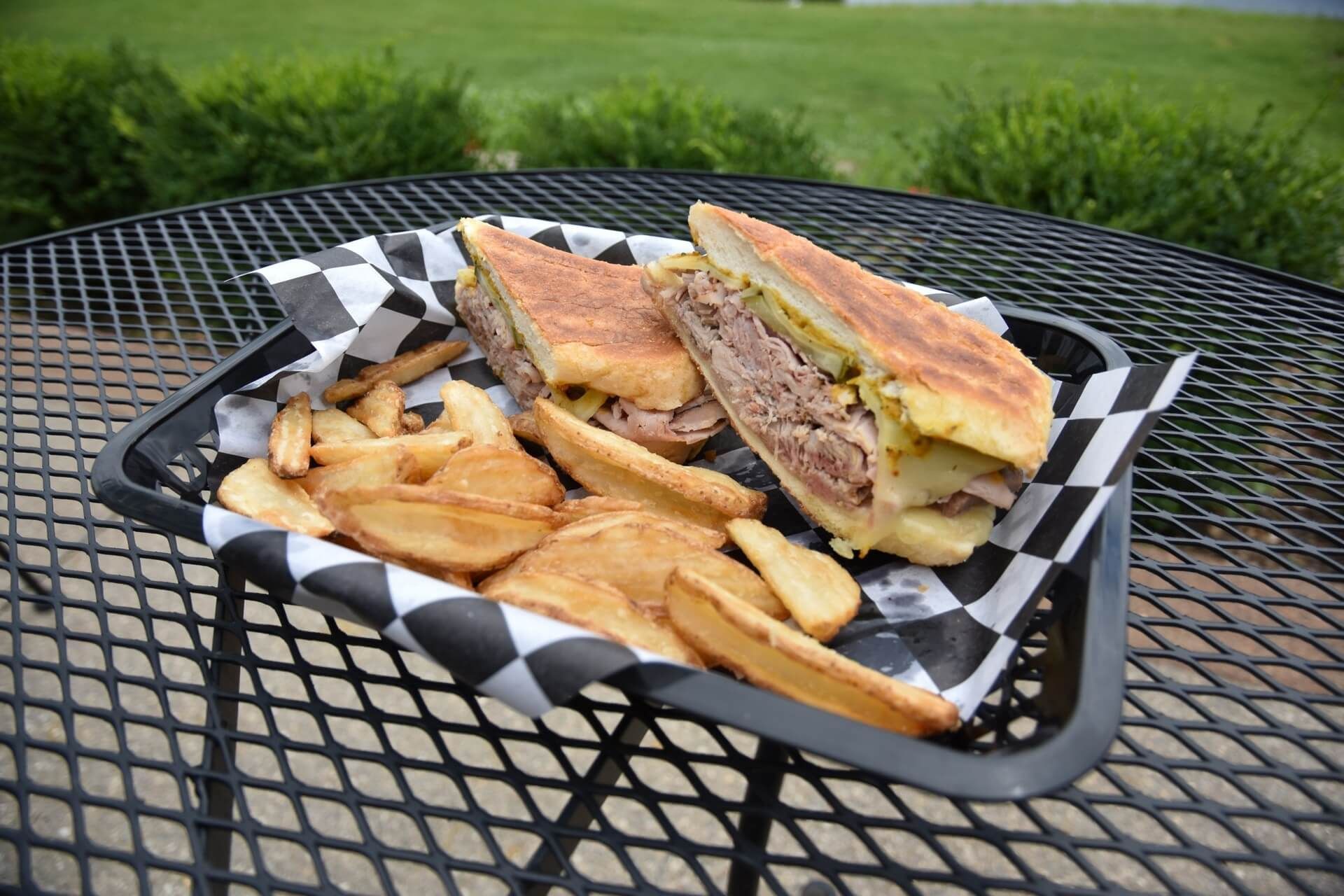 A sandwich and french fries in a basket on a table.