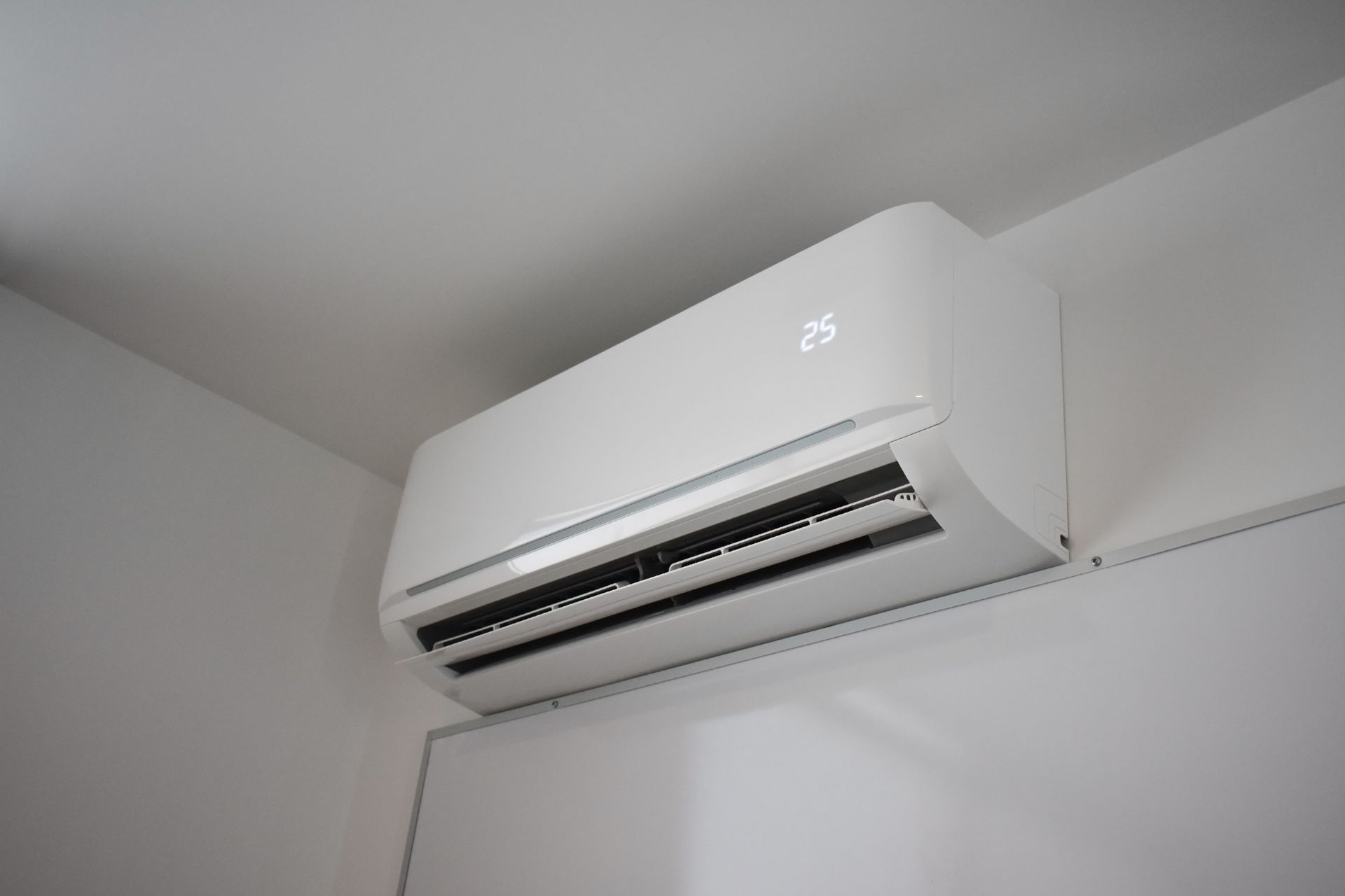 White wall-mounted air conditioner with digital temperature display.