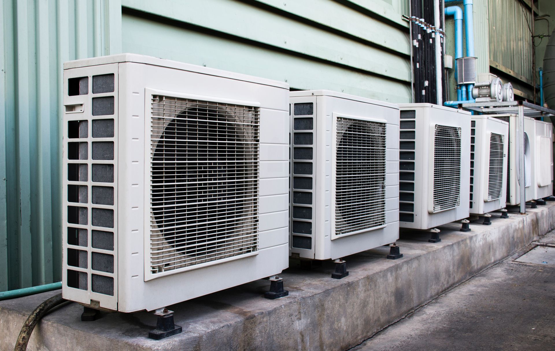 Row of air conditioning units against a building wall.