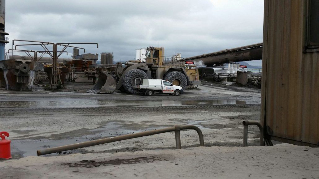 A white truck is parked in front of a large bulldozer
