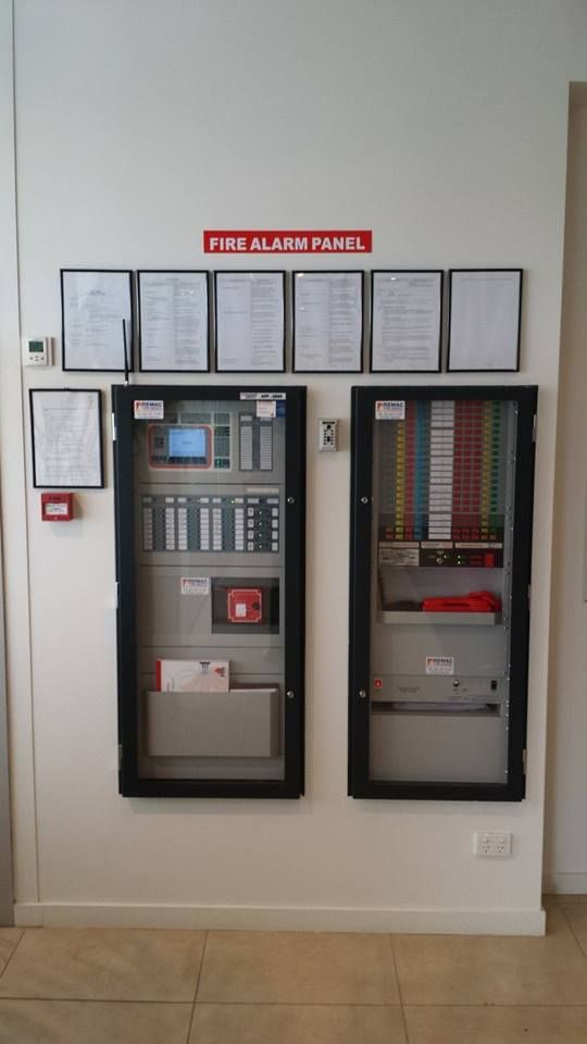 Two fire alarm panels are hanging on a wall.