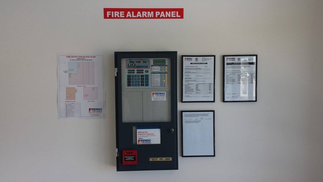 A fire alarm panel is hanging on a white wall