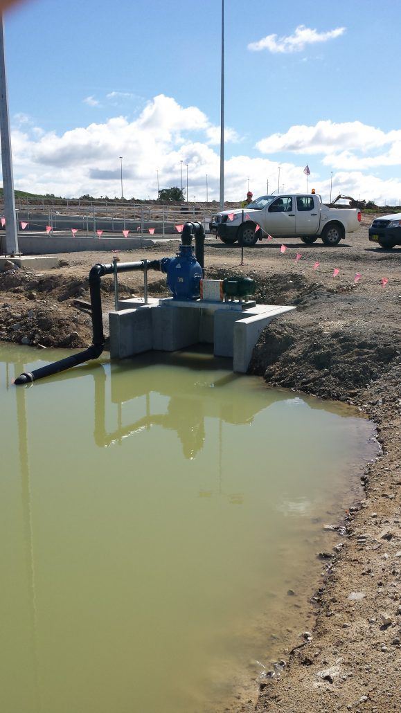 A large body of water is in the middle of a dirt field.