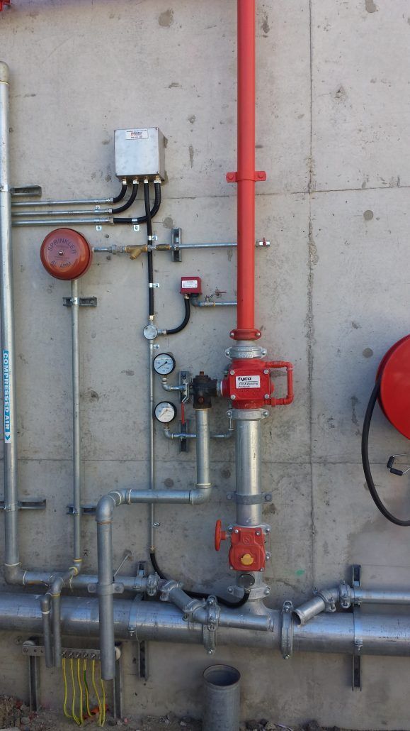 A concrete wall with a bunch of pipes attached to it