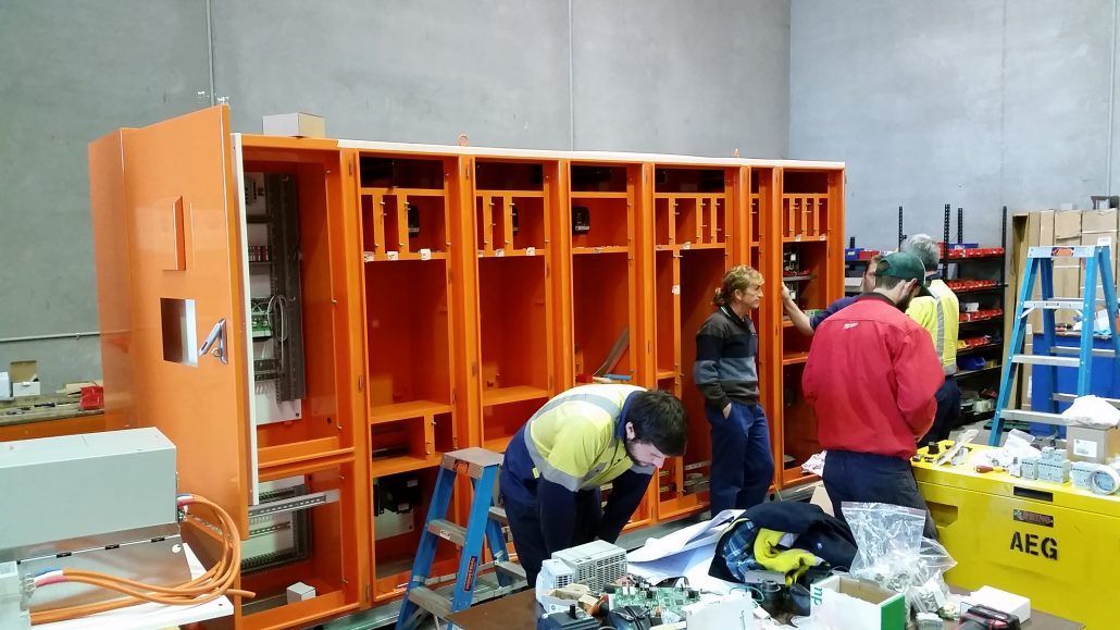 A group of people are working on a machine in a warehouse.