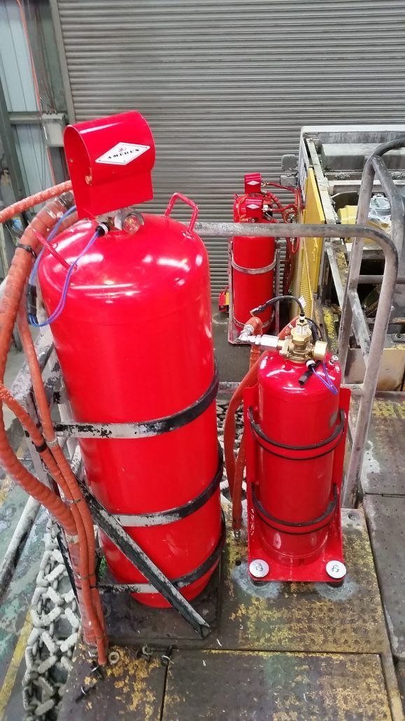 Two red fire extinguishers are sitting on top of a wooden platform.