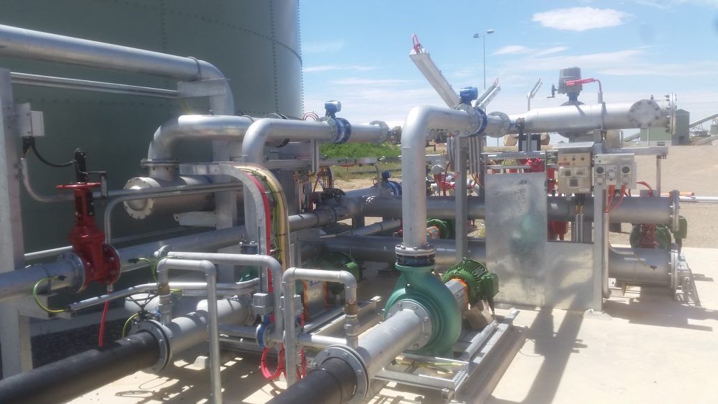 A bunch of pipes are sitting on the ground in a factory.