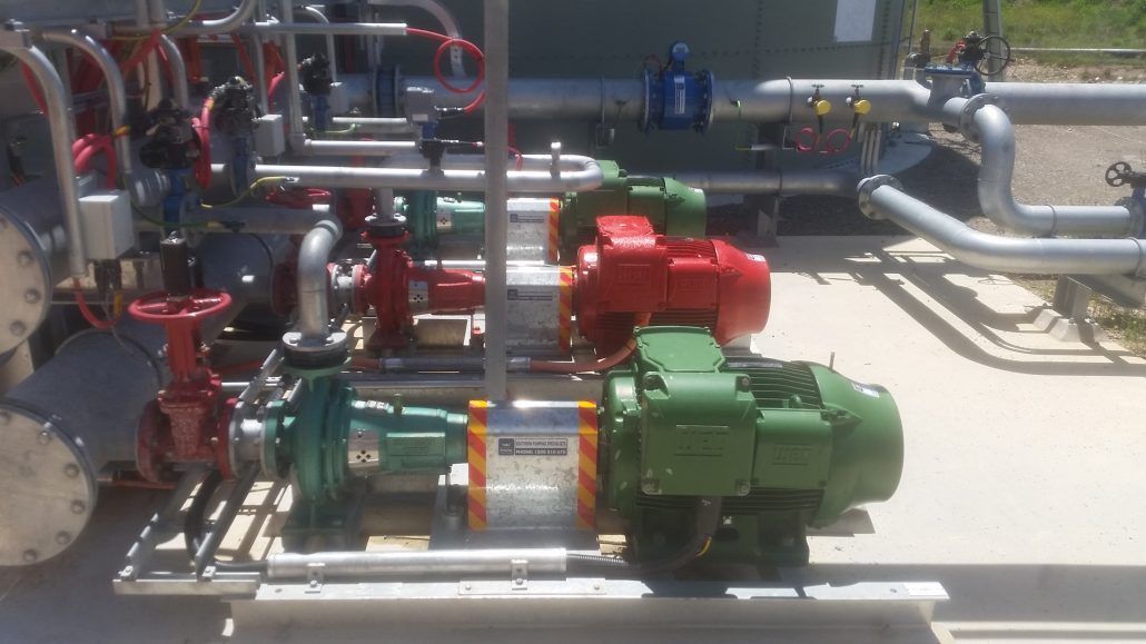 A bunch of pumps and pipes are sitting on the ground in a factory.