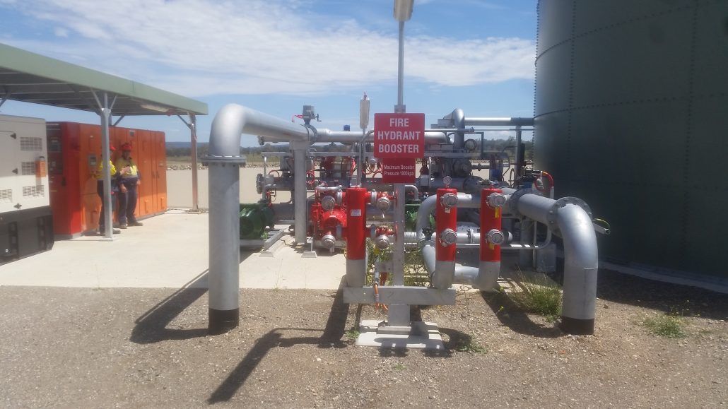 A bunch of pipes are sitting on the ground in a field.