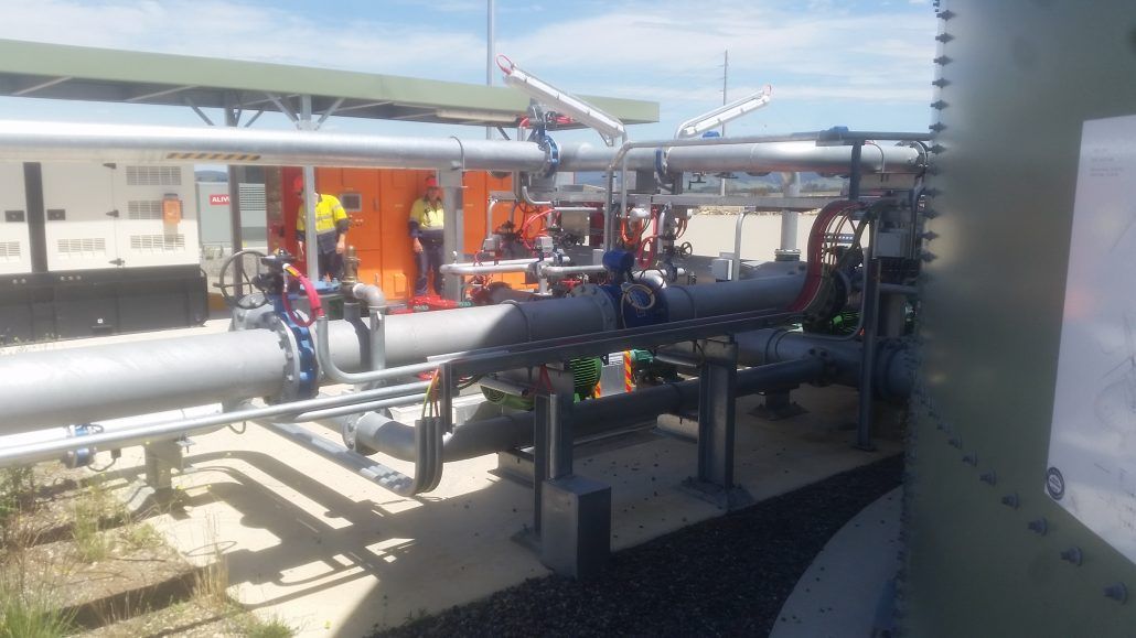 A group of people are working on a large pipe in a factory.