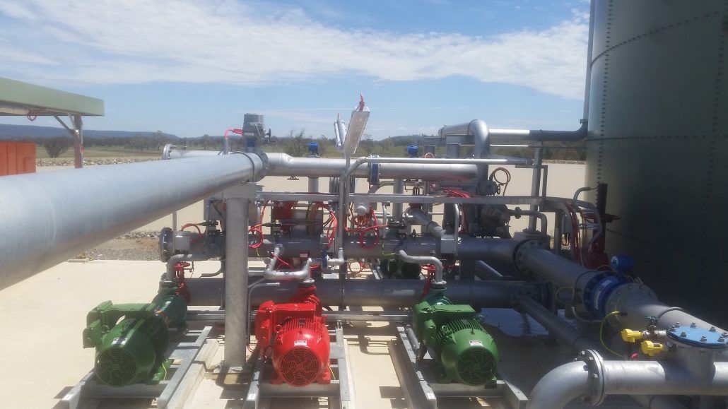 A bunch of pipes and pumps are sitting next to each other in a factory.