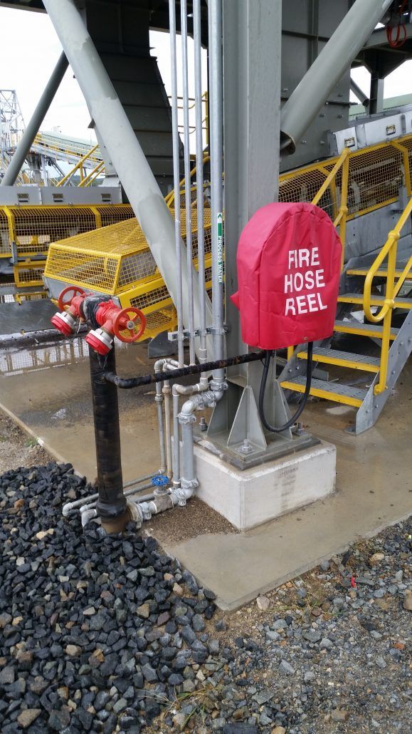 A red fire hose reel is sitting on the ground next to a staircase.