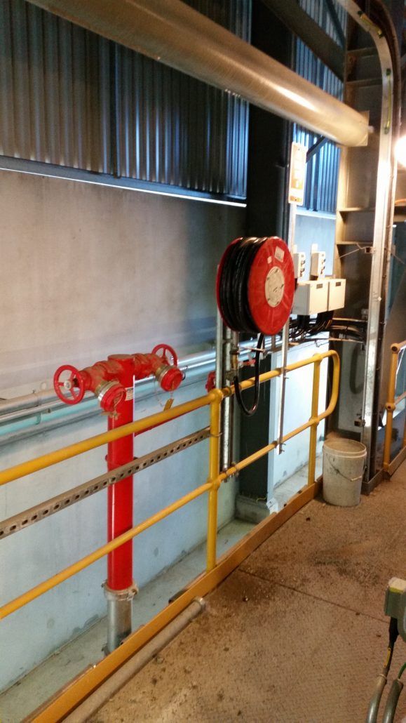 A red fire hydrant is sitting next to a yellow railing in a building.