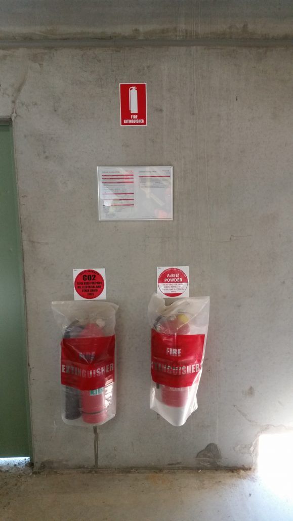 Two bags of fire extinguishers are hanging on a wall.