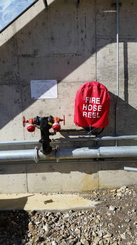 A red fire hose reel is attached to a pipe.