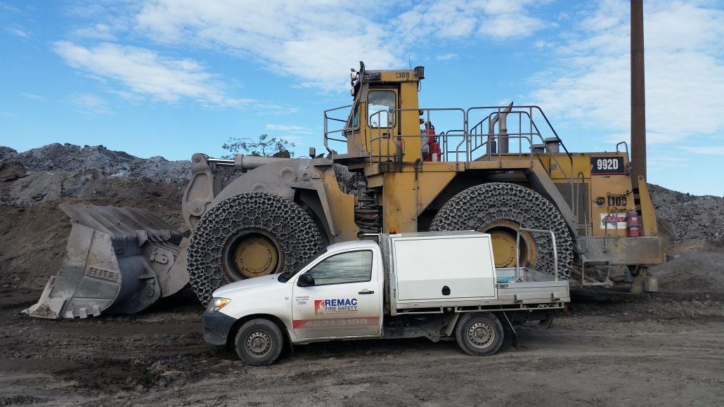 A white truck is parked in front of a bulldozer.