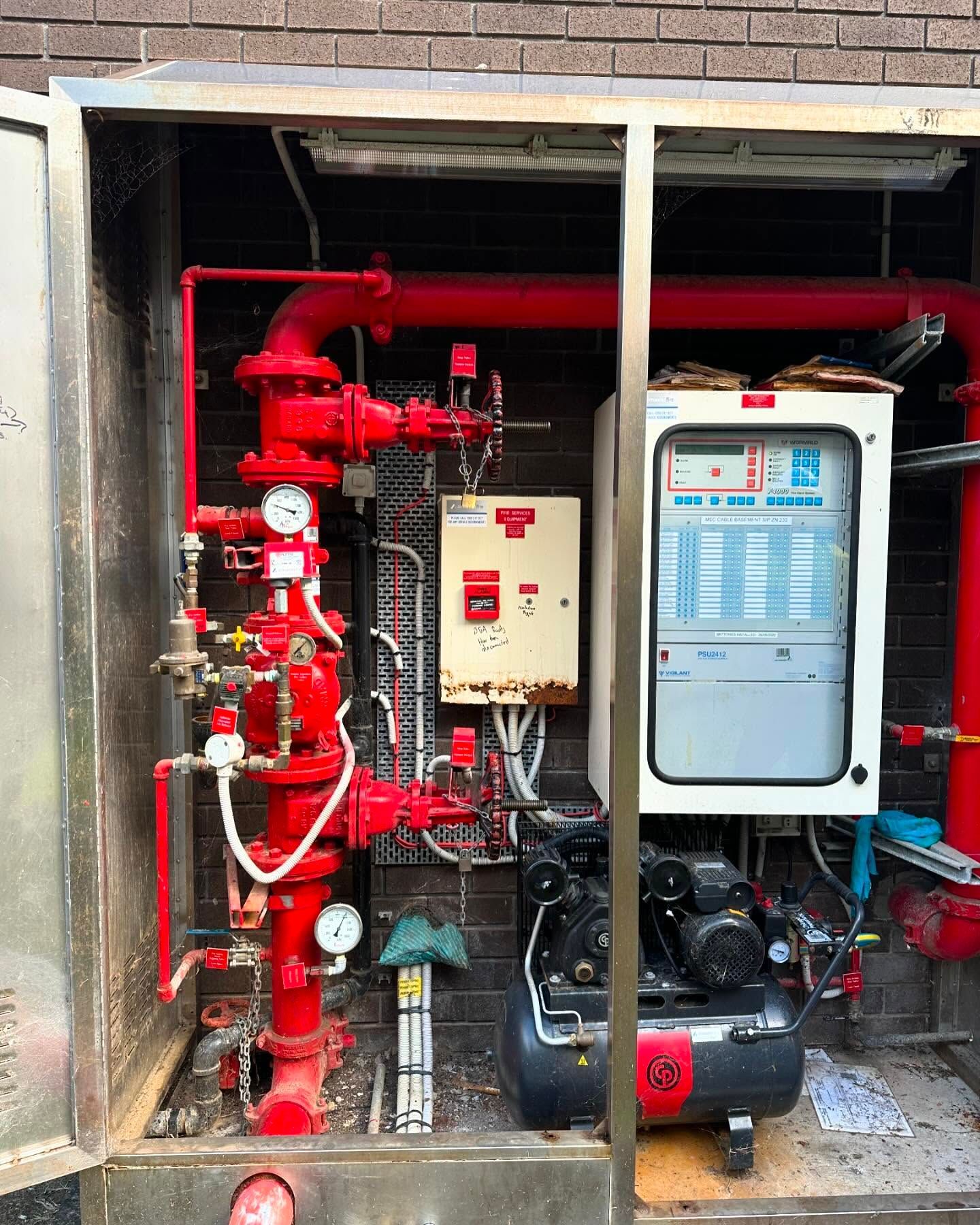 A stainless steel box filled with red pipes and a compressor.