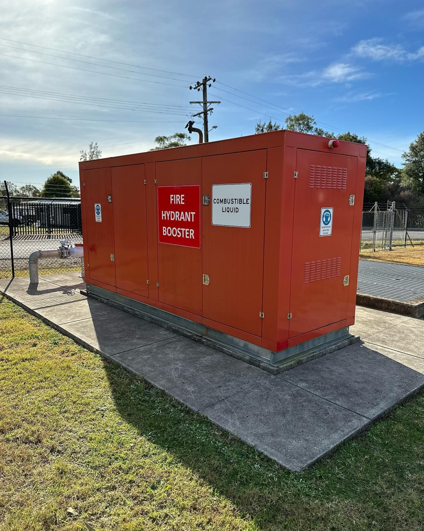 A large red box is sitting on top of a concrete platform in a grassy area.