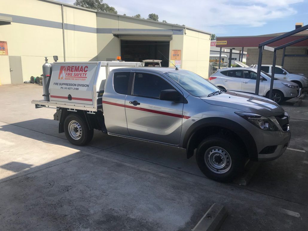 A silver truck is parked in a parking lot in front of a building.