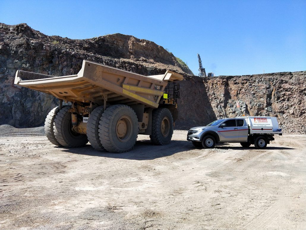 A large dump truck is parked next to a white truck