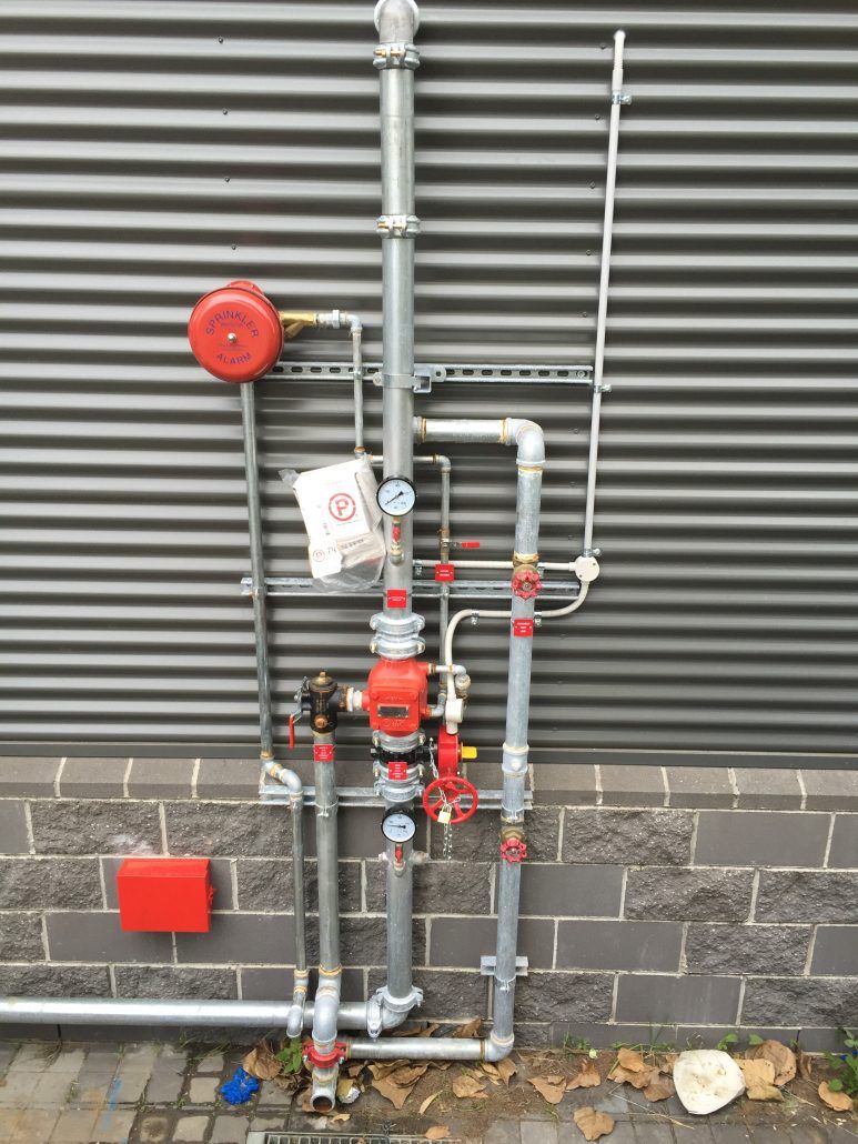 A fire hydrant is attached to the side of a building.