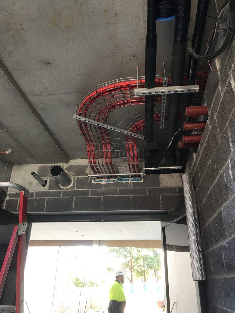 A man is standing in a room with a bunch of wires hanging from the ceiling.