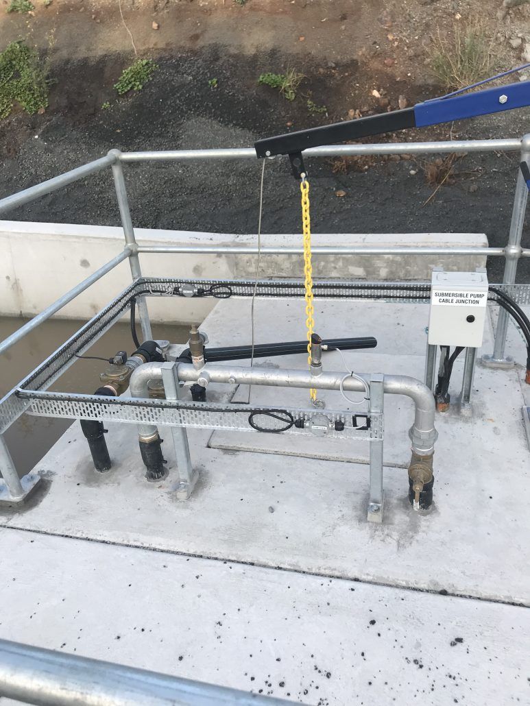 A concrete platform with a metal railing and pipes on it