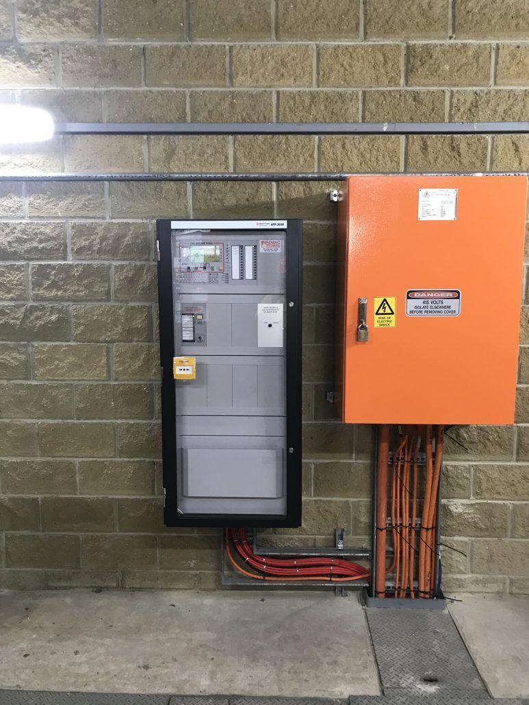 A large orange box is hanging on a brick wall.