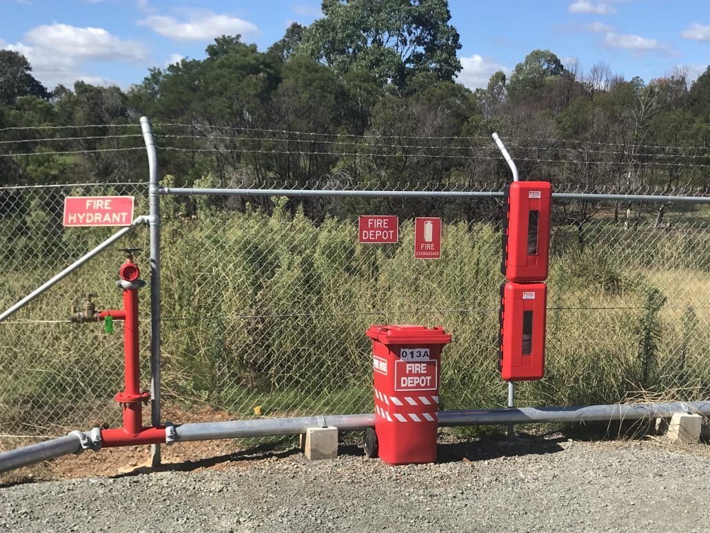 A red fire hydrant is sitting in front of a chain link fence.