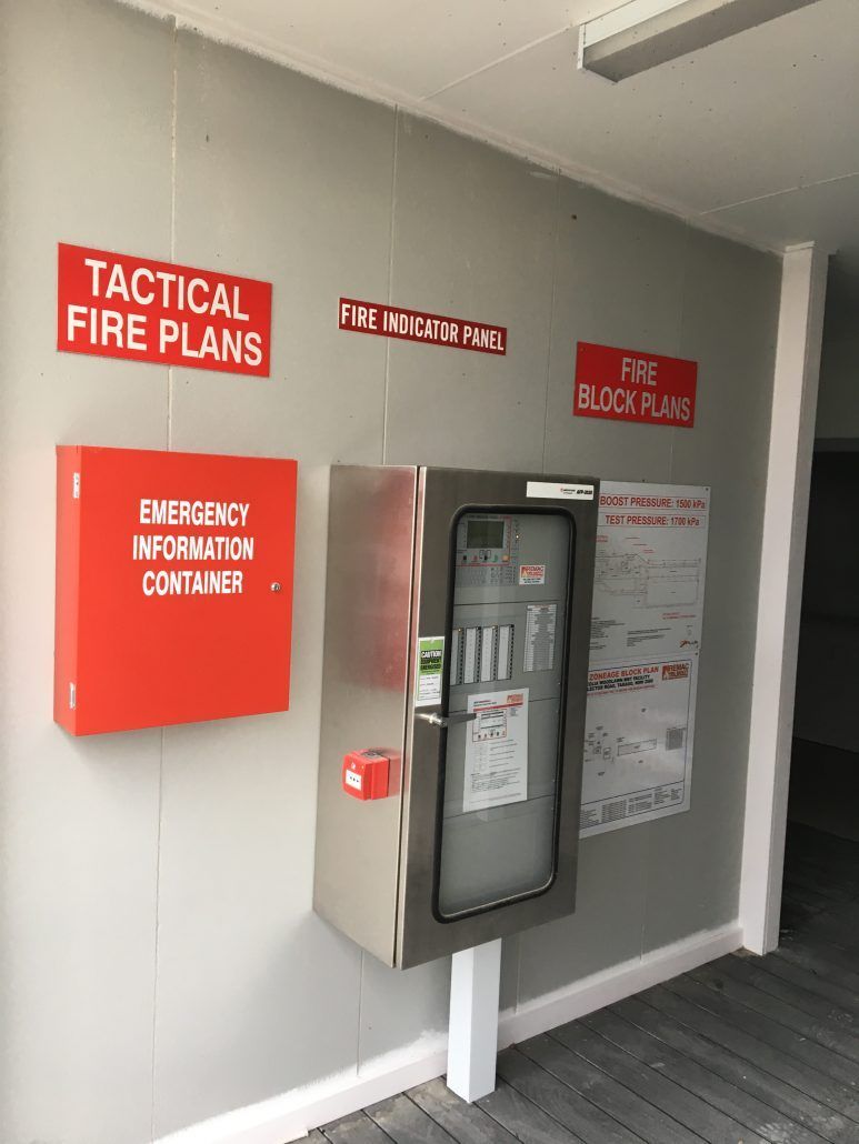 A tactical fire plans sign is on a wall next to an emergency information container