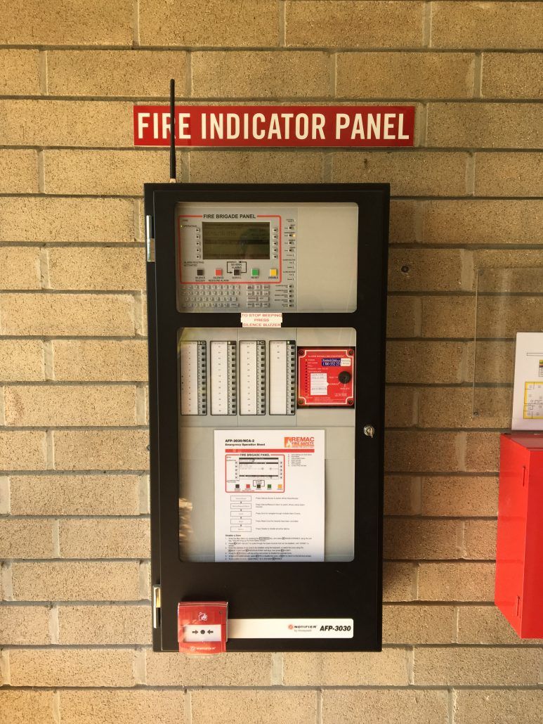 A fire indicator panel is mounted on a brick wall