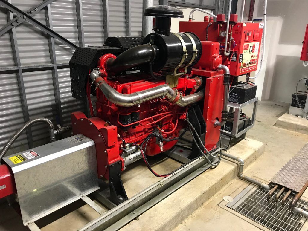 A large red engine is sitting in a room next to a wall.