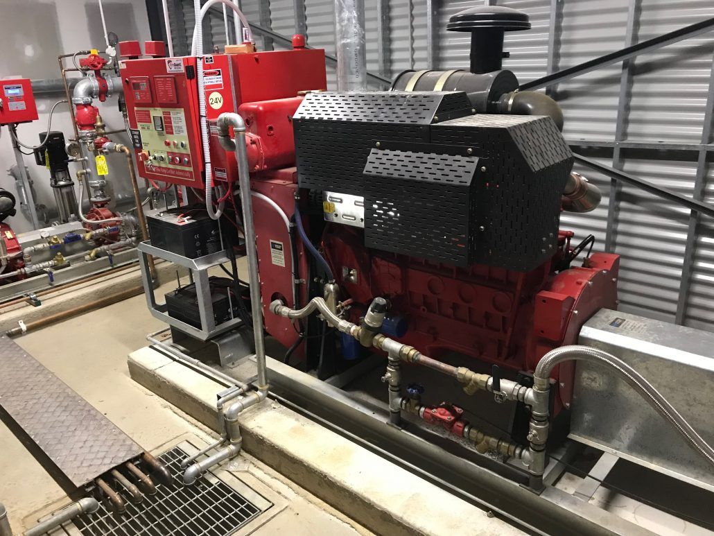 A red engine is sitting on top of a concrete floor in a room.