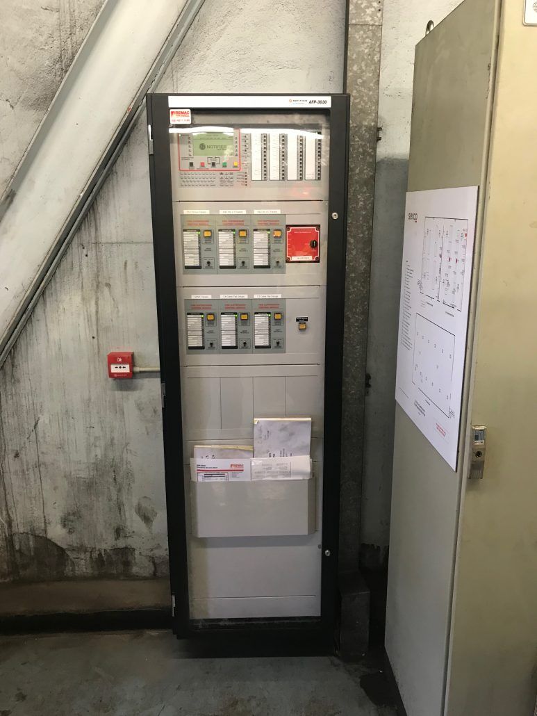 A large electrical panel is sitting in a room next to a door.