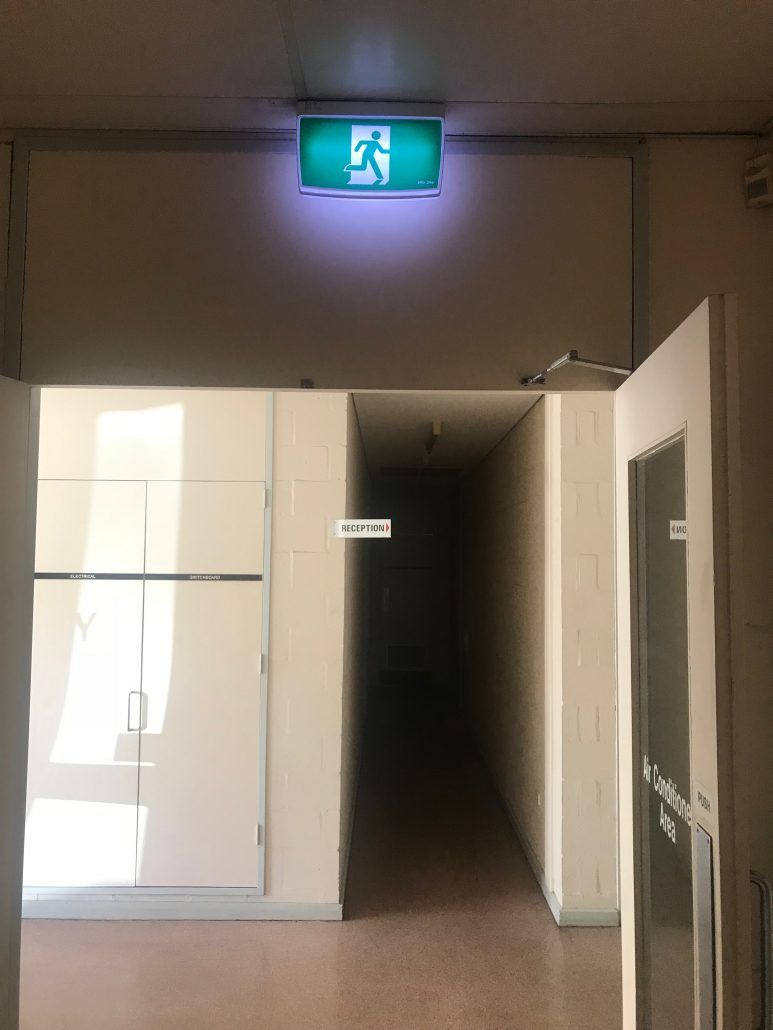 A hallway with a green exit sign above it