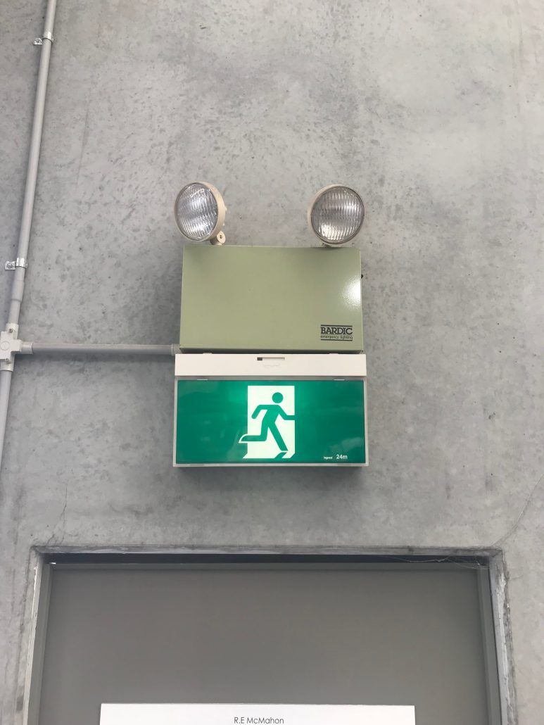 A green exit sign is hanging on a wall above a door.