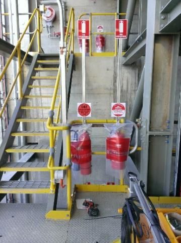 A staircase with a yellow railing and red fire extinguishers