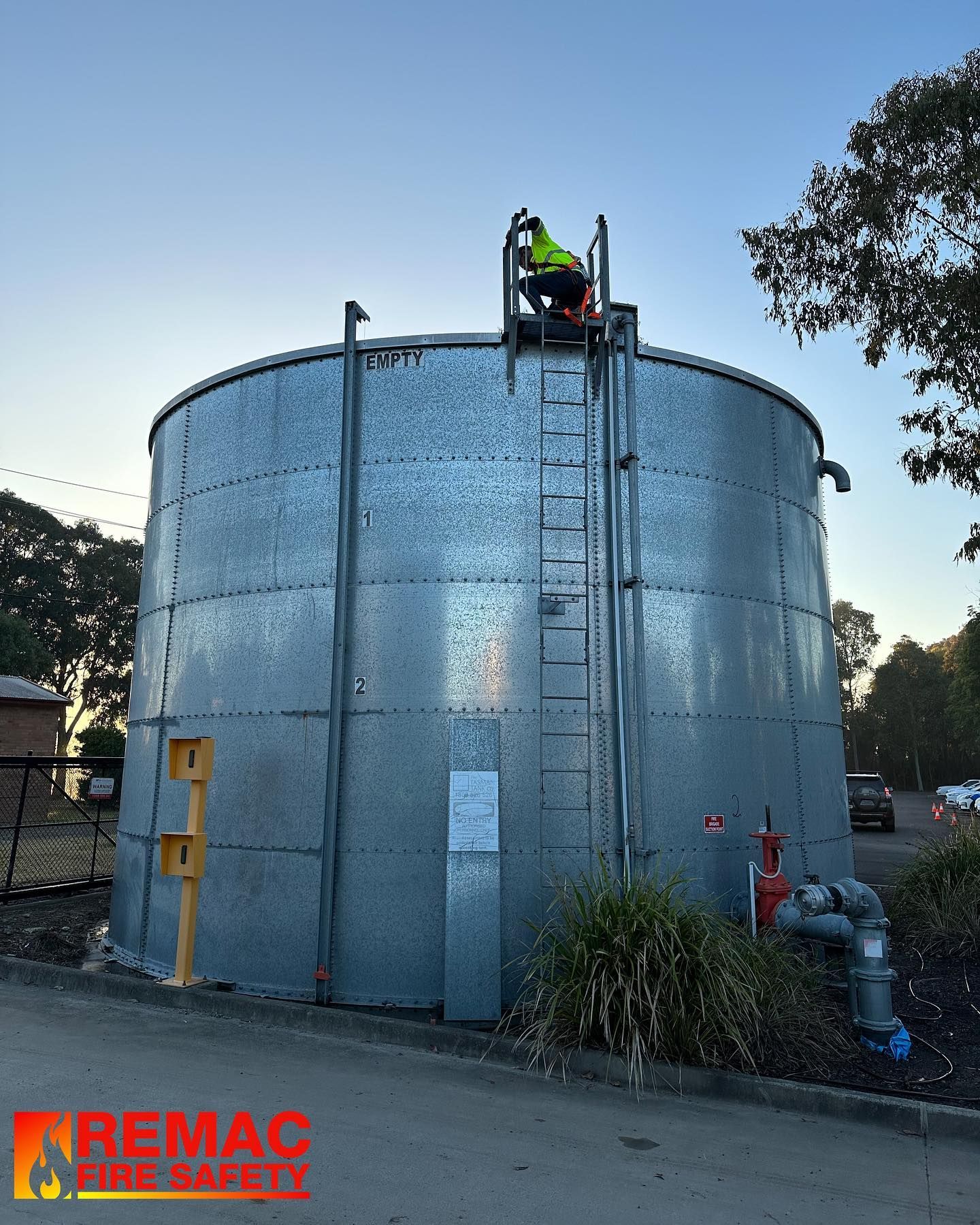 A man is standing on top of a large metal tank