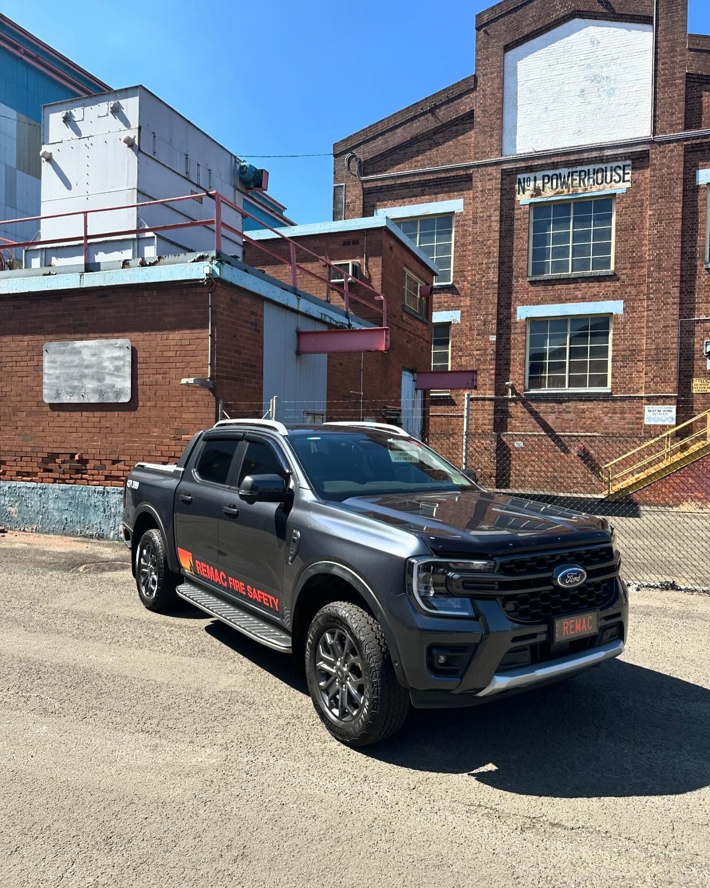 A black truck is parked in front of a brick building.