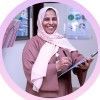 A woman in a hijab is holding a clipboard and smiling.