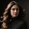 A woman with long hair is wearing a black turtleneck and looking at the camera.
