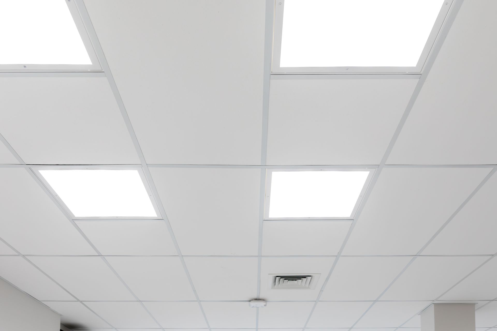 Bright drop ceiling with recessed lighting panels and a small air vent. Bright drop ceiling with recessed lighting panels and a small air vent.