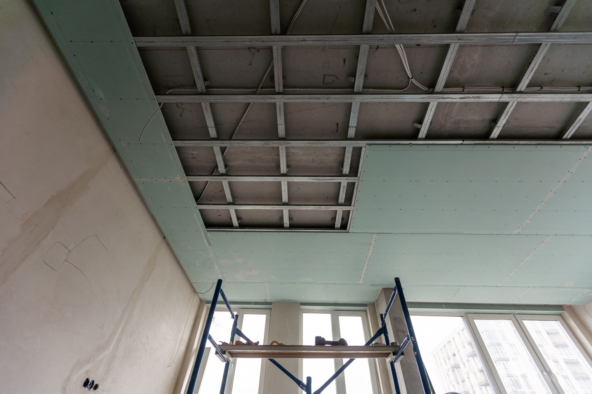 Drop ceiling under construction showing exposed metal grid and partially installed panels.