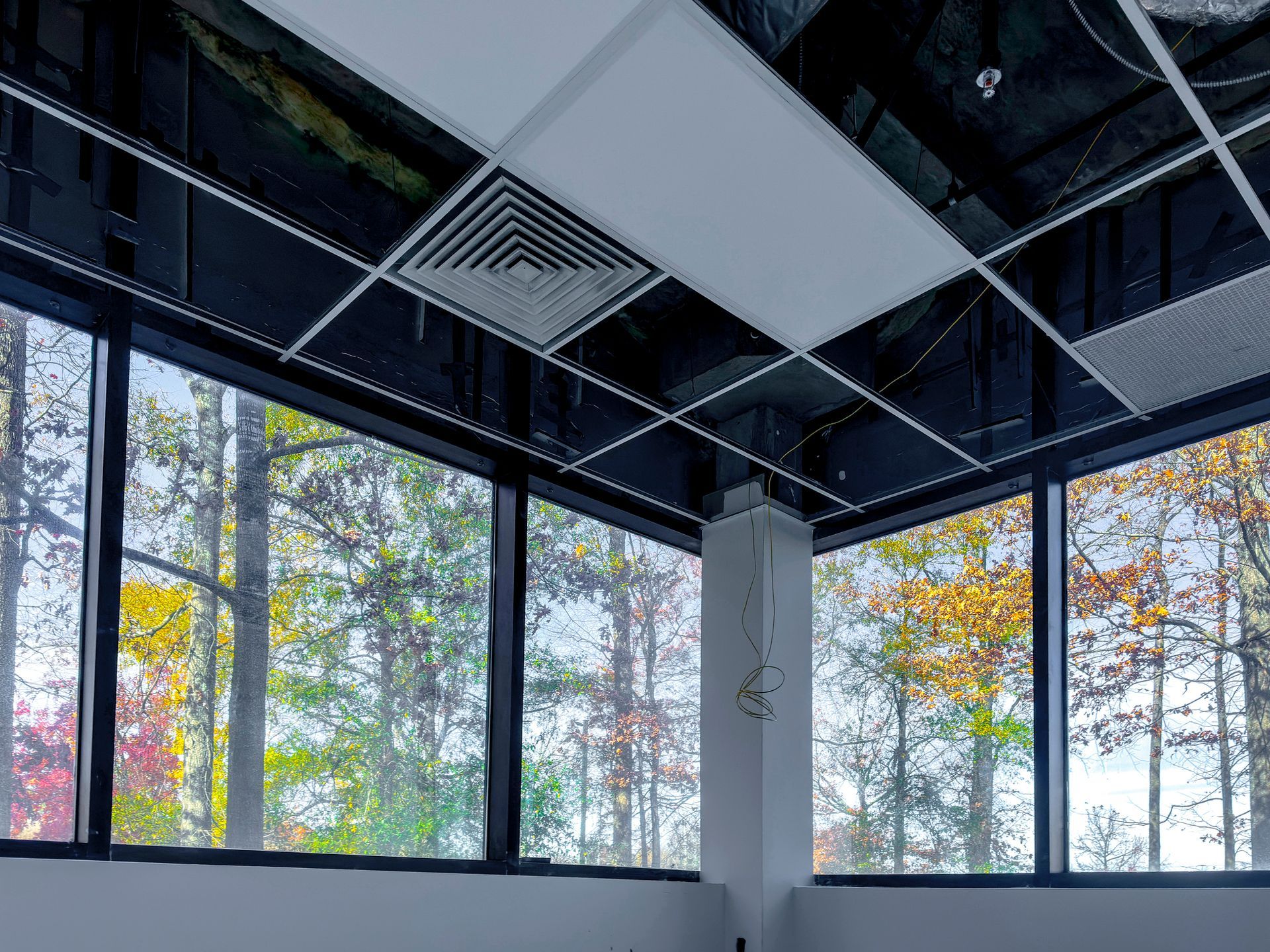 Office with drop ceiling panels, some removed to show wiring, and large windows. Office with drop ceiling panels, some removed to show wiring, and large windows.
