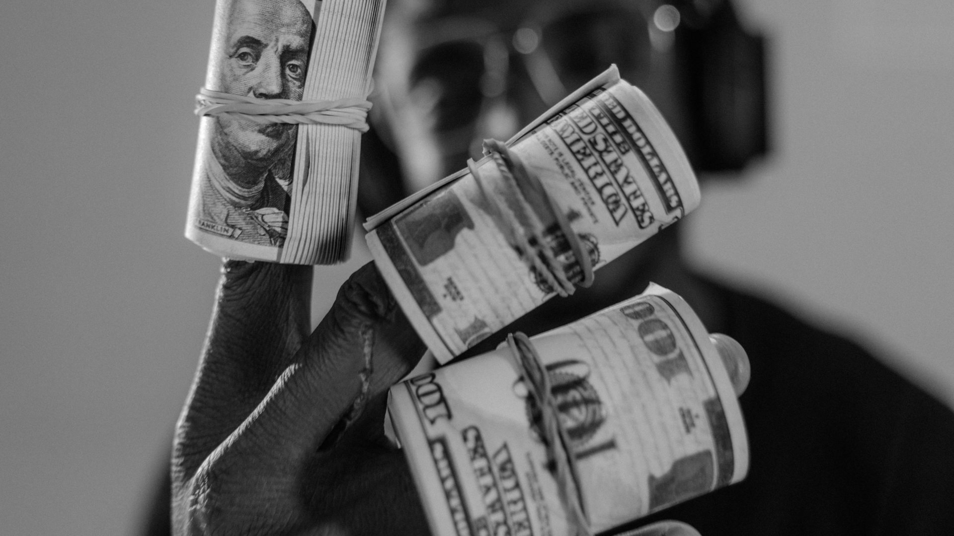 Person holding rolls of money, black and white.