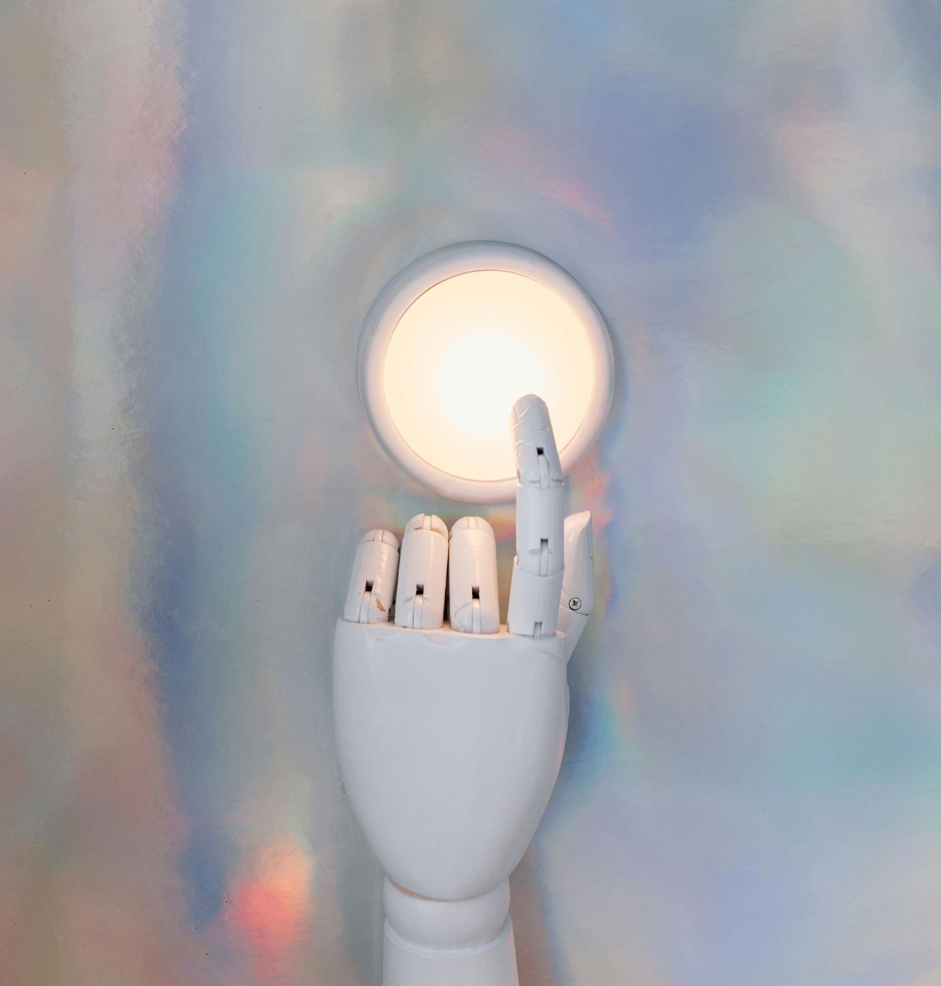 A white mannequin hand is holding a light bulb.